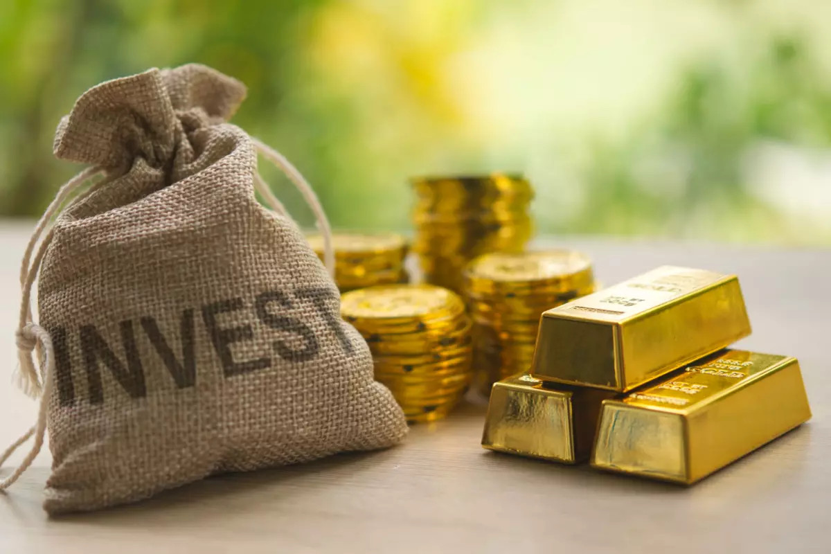 Gold bars and coins next to a bag with "invest" on it